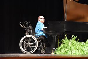 guest speaker Patrick Henry Hughes at piano on stage